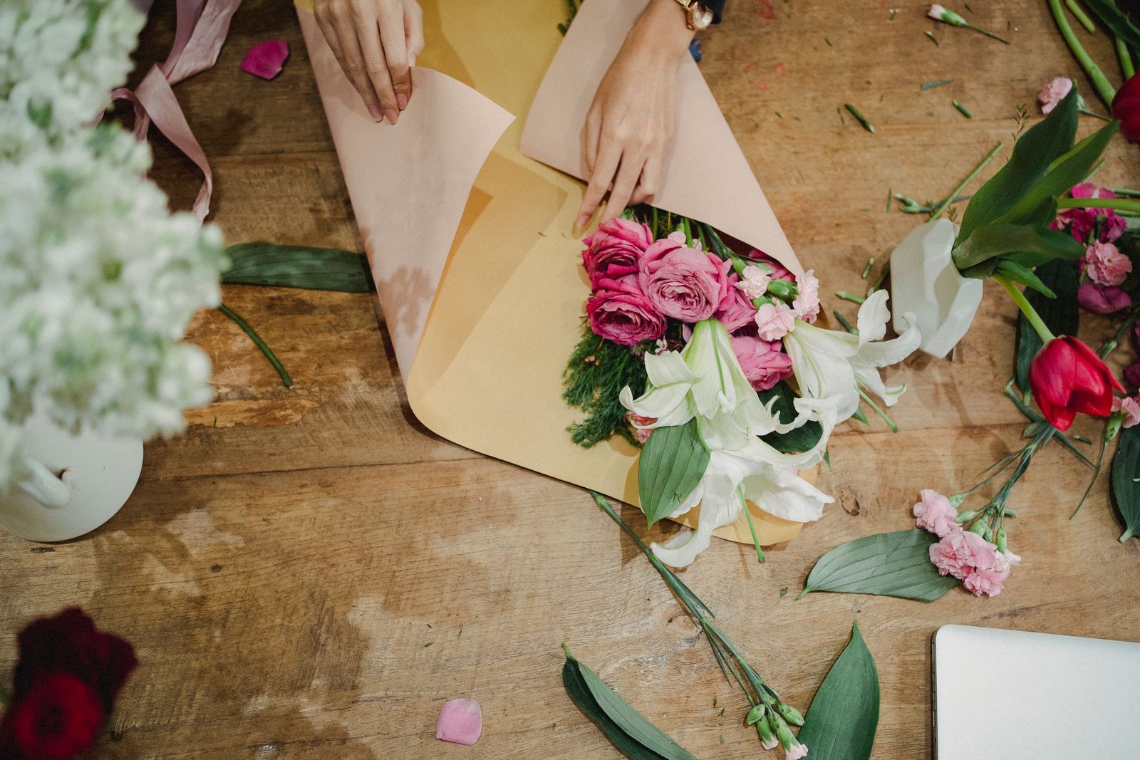 Composition d’un bouquet sur l’établi d’un atelier de fleuriste, papier d’emballage et fleurs coupées