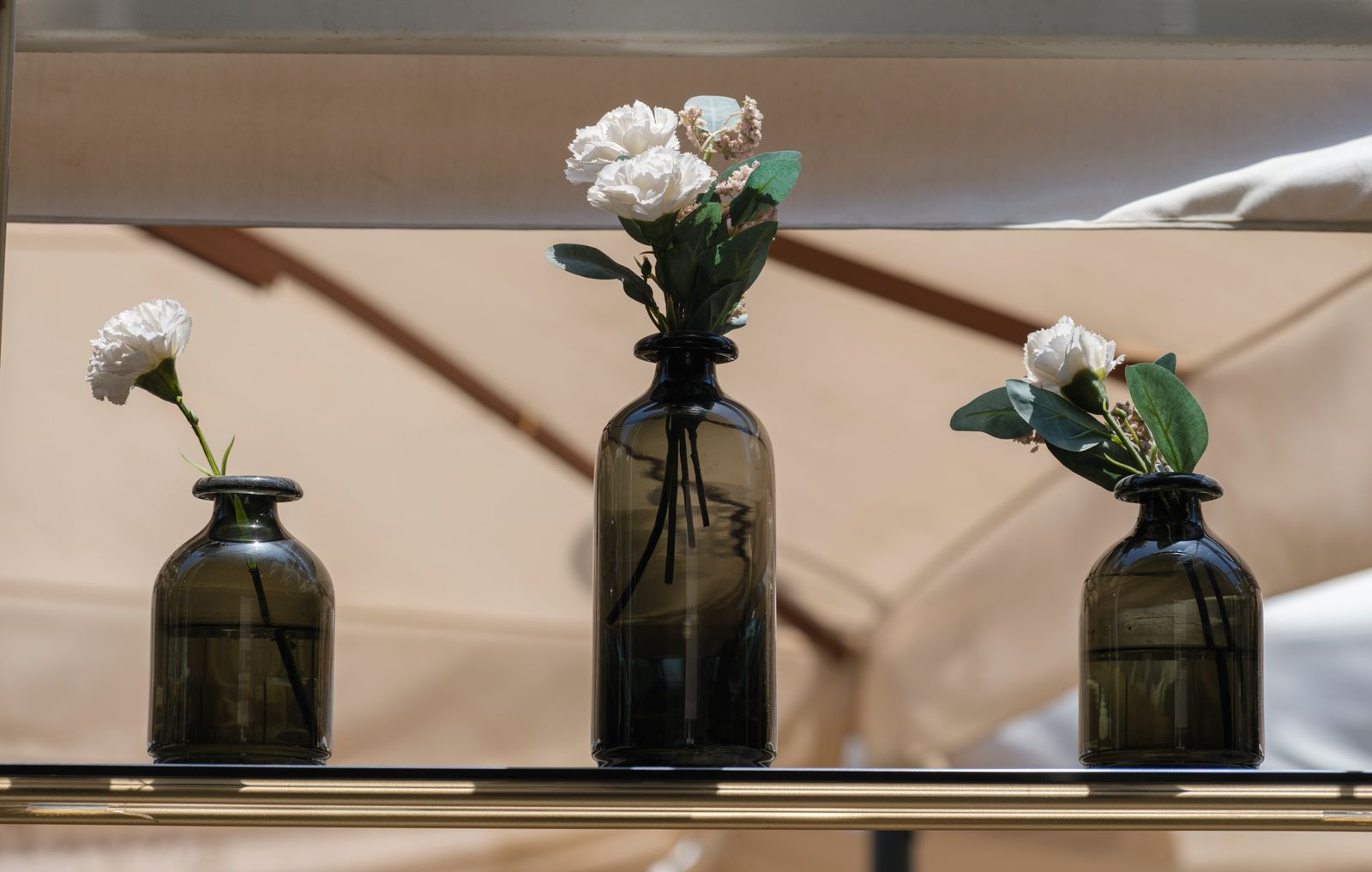 Trois vases en verre garnis de fleurs blanches, composition sobre